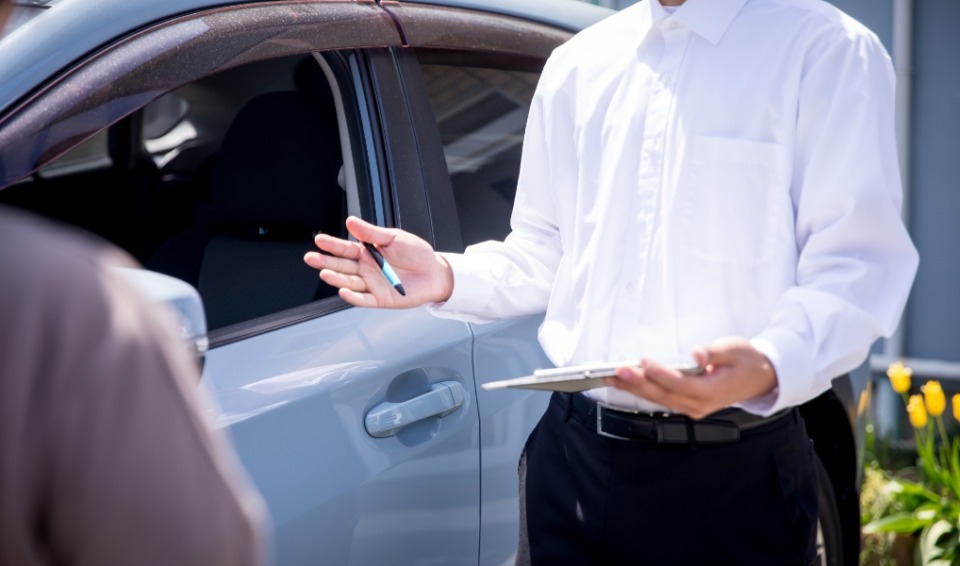 車の前で男性が指導を受けている写真